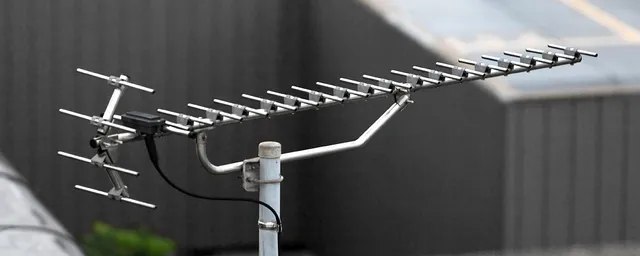Antena Yagi-Uda UHF exterior, con varios elementos directores y un reflector, montada sobre un mástil